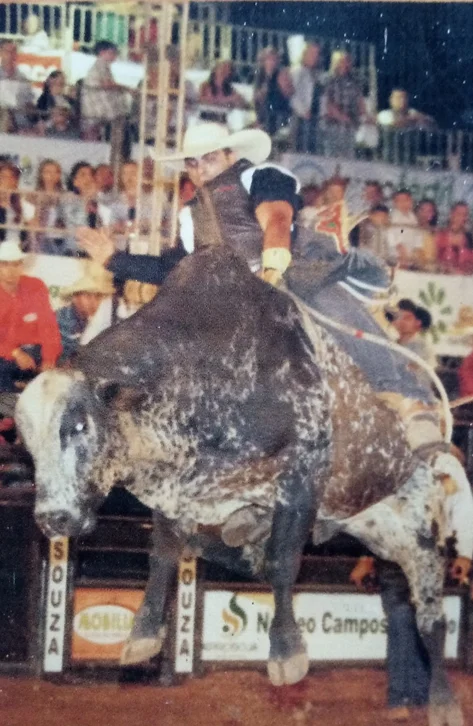 Rafael montando em touro em arena de rodeio